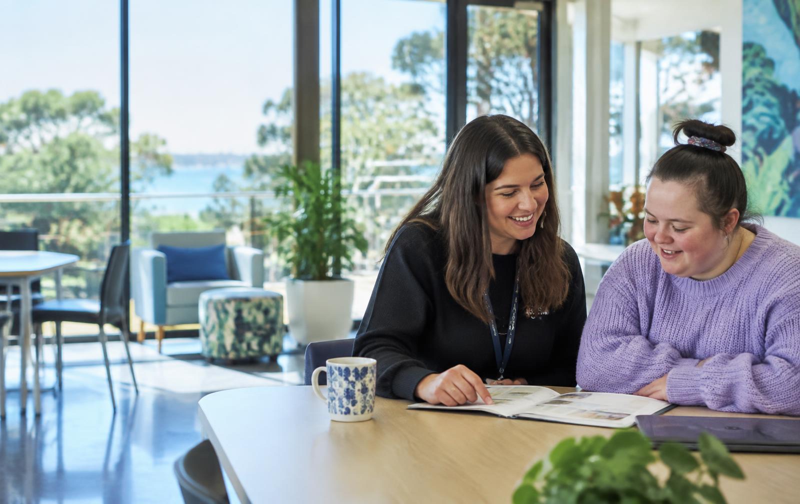 Two people discussing a support plan together in a bright community space